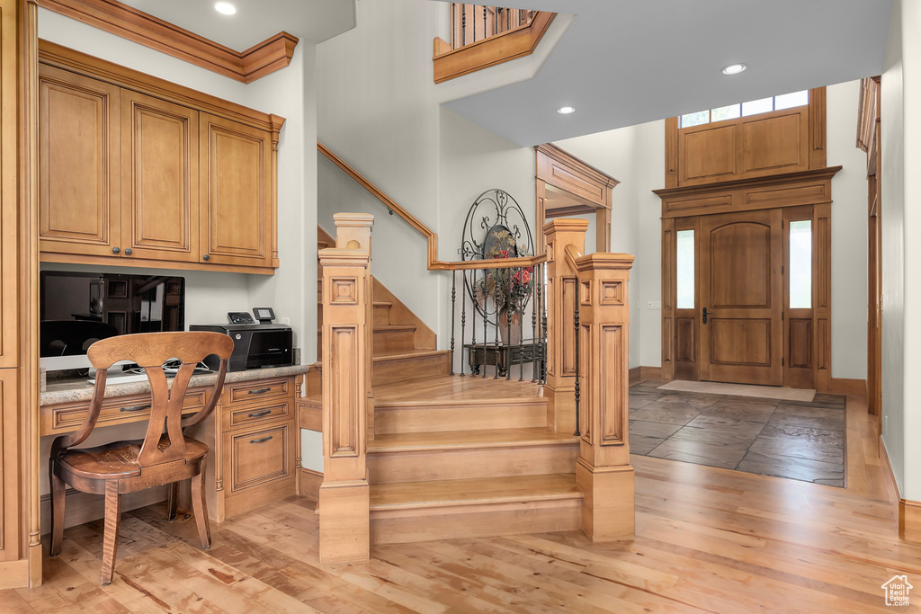 Foyer entrance featuring built in desk, hardwood / wood-style floors, and crown molding