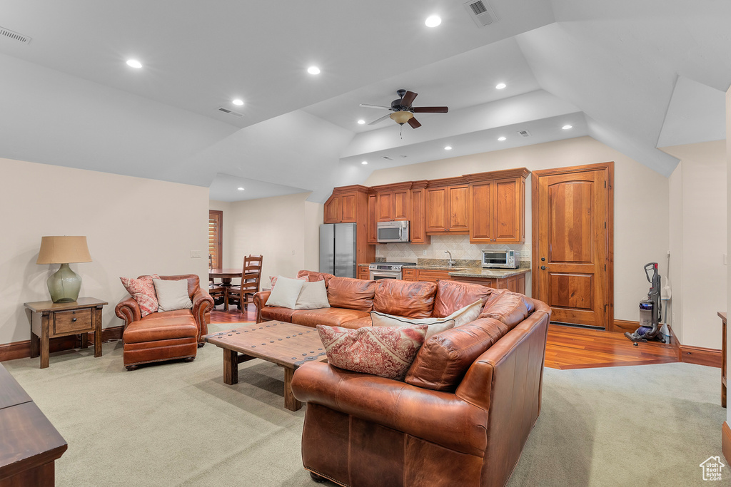 Carpeted living room with ceiling fan, sink, and vaulted ceiling