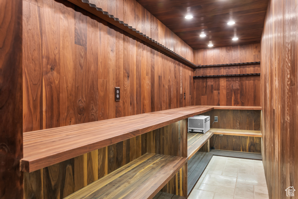 View of sauna with wooden ceiling, tile patterned floors, and wooden walls