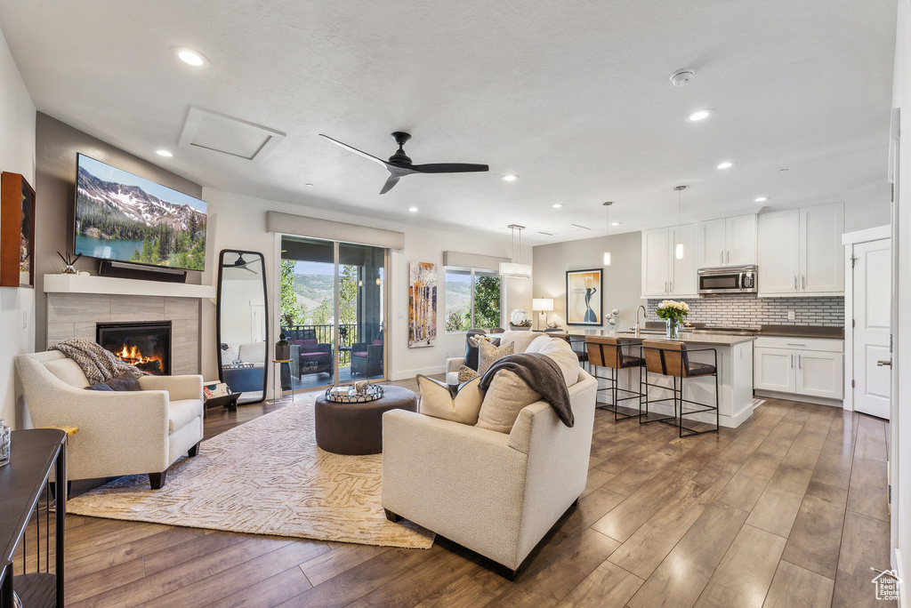 Living room featuring ceiling fan, a tile fireplace, and hardwood / wood-style flooring