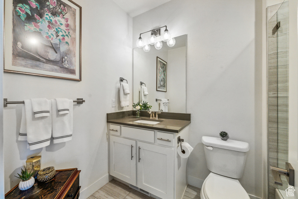 Bathroom featuring vanity, toilet, wood-type flooring, and a shower with door