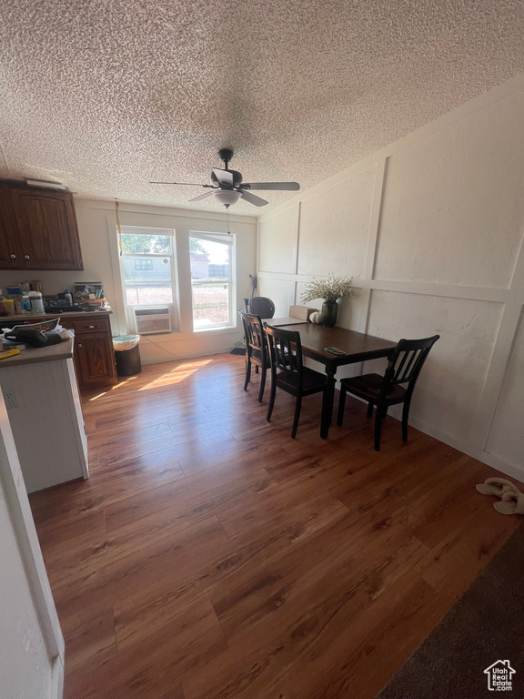 Dining room with hardwood / wood-style floors, ceiling fan, and a textured ceiling