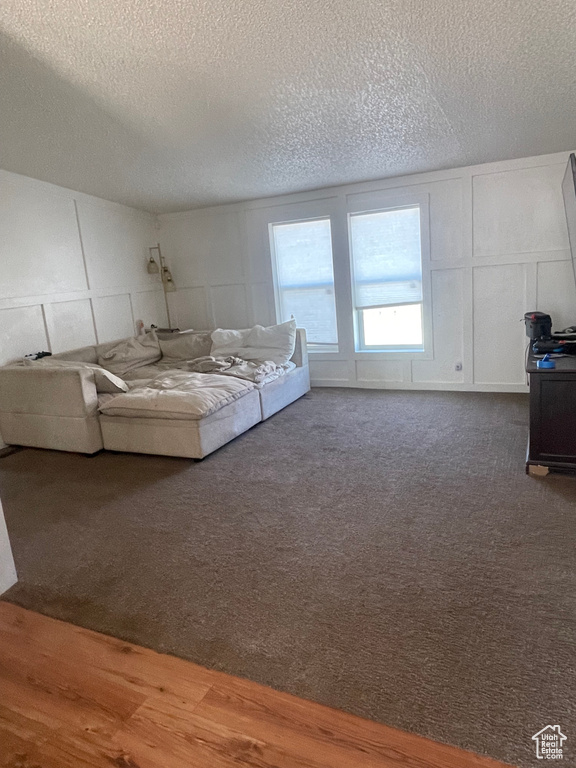 Unfurnished living room featuring hardwood / wood-style flooring and a textured ceiling