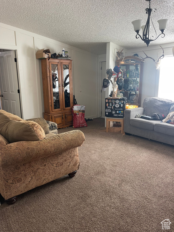 Living room featuring a textured ceiling, a chandelier, and carpet flooring