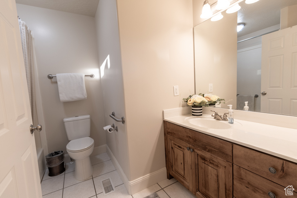 Bathroom with tile patterned flooring, vanity, toilet, and walk in shower