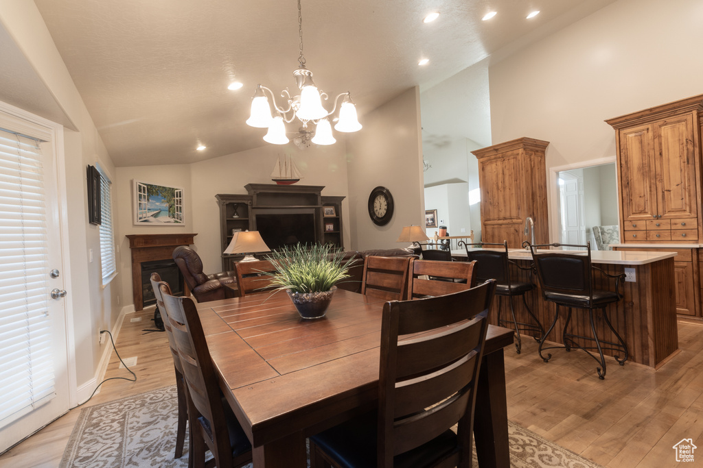 Dining area with light wood-type flooring, high vaulted ceiling, and a chandelier