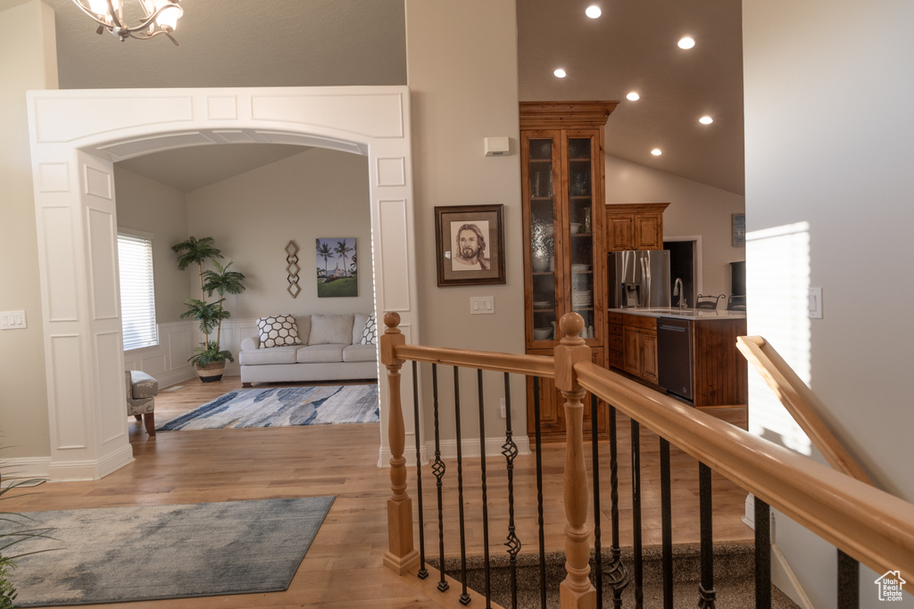 Corridor featuring vaulted ceiling, light hardwood / wood-style flooring, and a notable chandelier