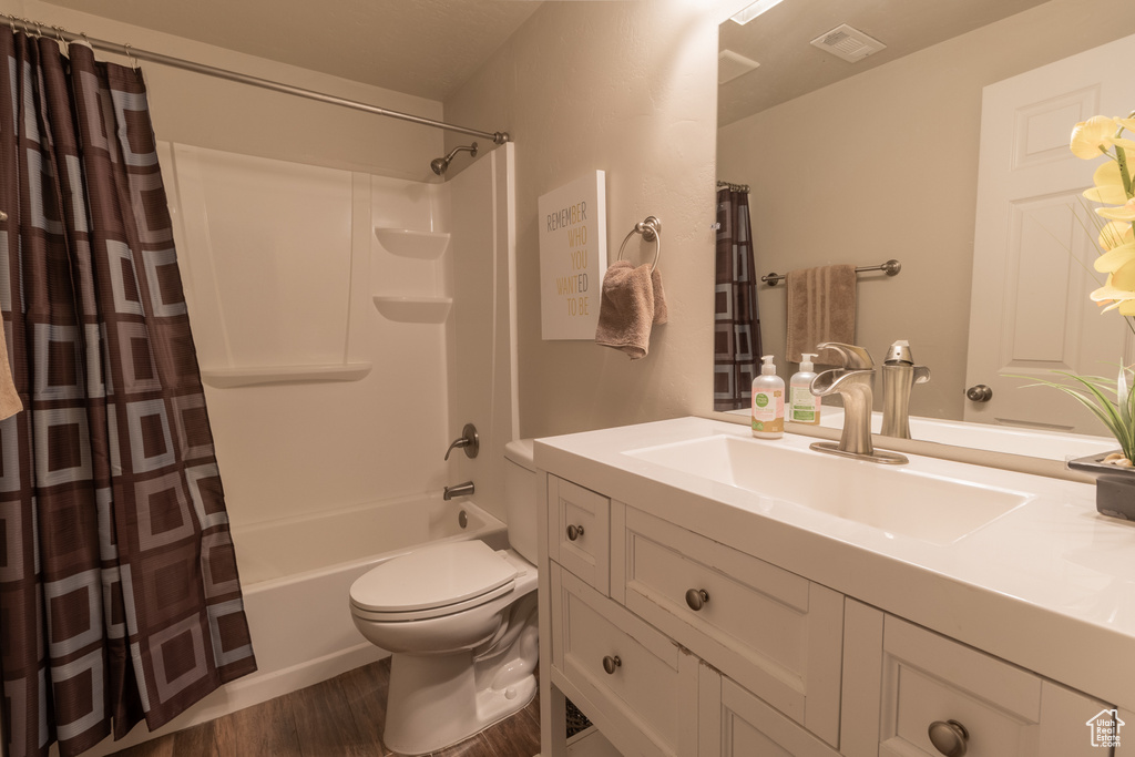 Full bathroom with shower / bath combo, hardwood / wood-style floors, toilet, and vanity