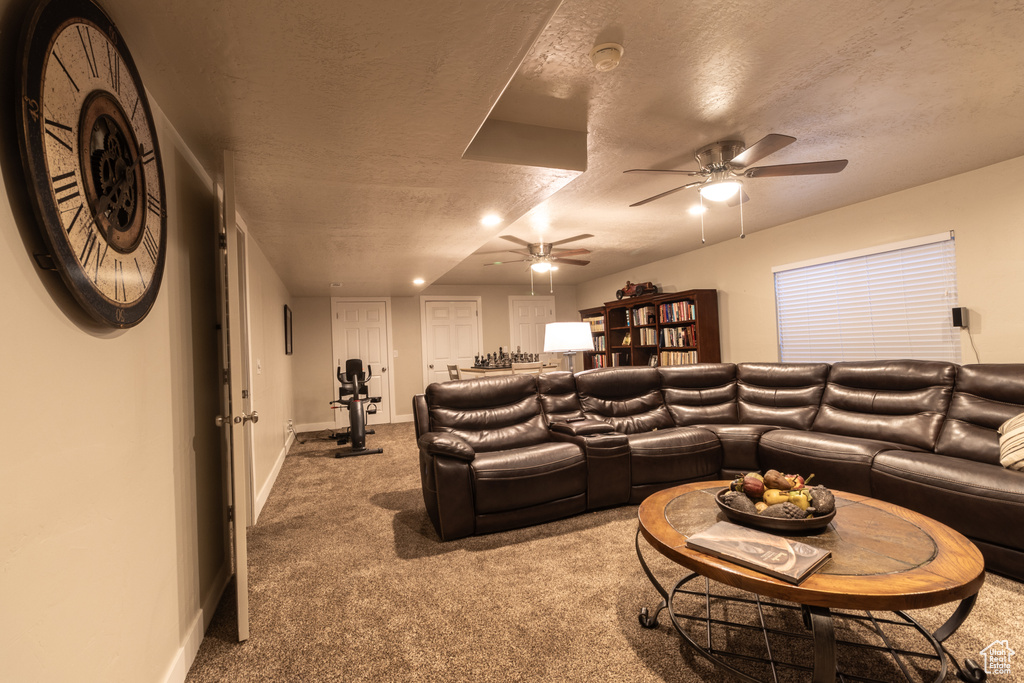 Carpeted living room featuring ceiling fan and a textured ceiling