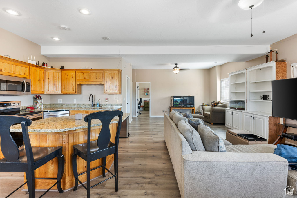 Kitchen featuring stainless steel appliances, light hardwood / wood-style floors, sink, a kitchen bar, and a kitchen island