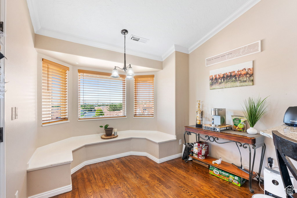 Dining space with dark wood-type flooring, a chandelier, and crown molding