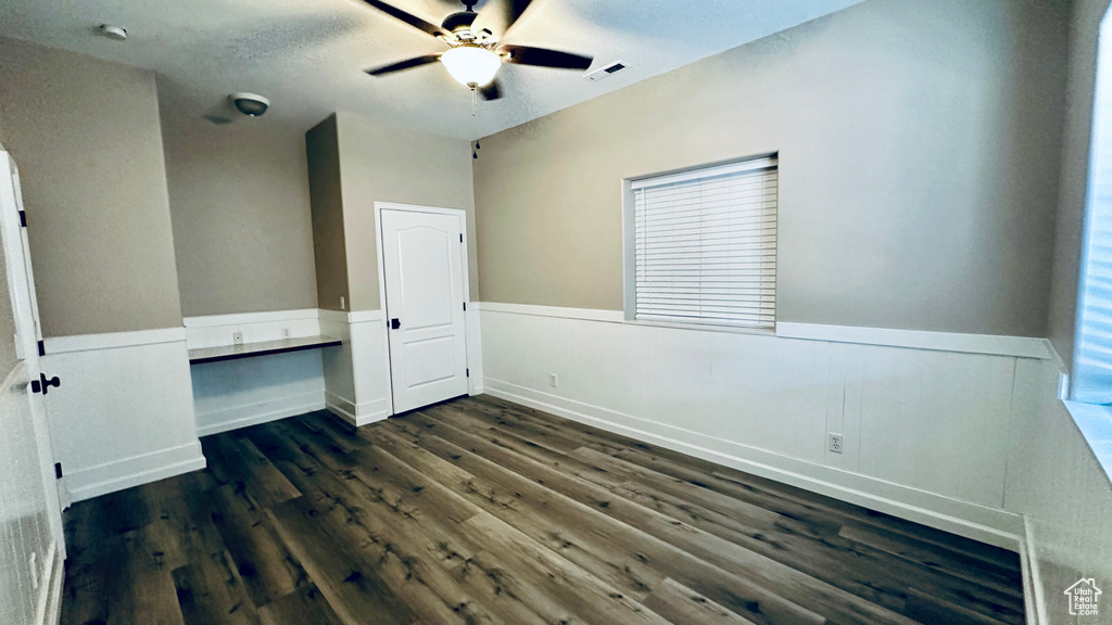 Unfurnished bedroom featuring ceiling fan, a textured ceiling, and dark hardwood / wood-style flooring