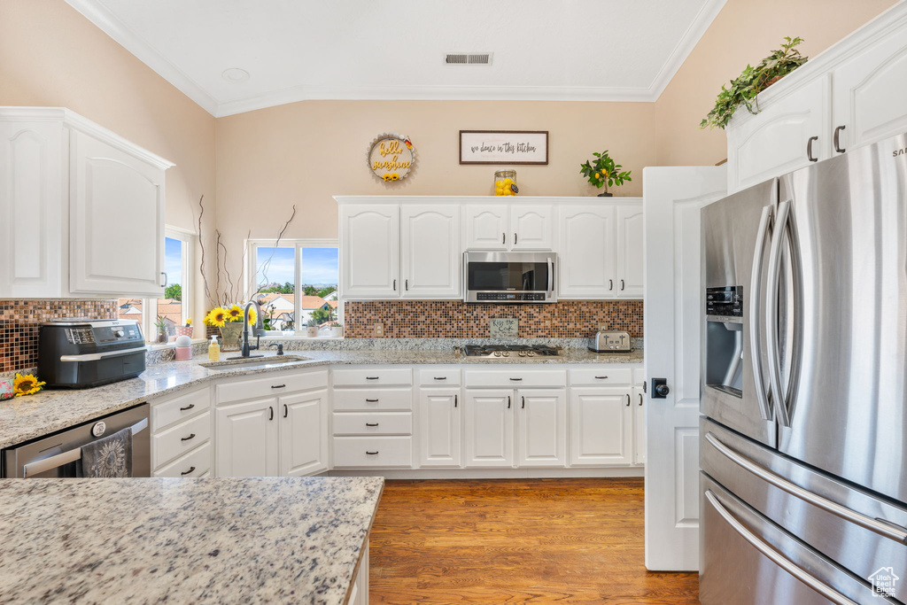 Kitchen featuring white cabinets, hardwood / wood-style flooring, crown molding, appliances with stainless steel finishes, and sink