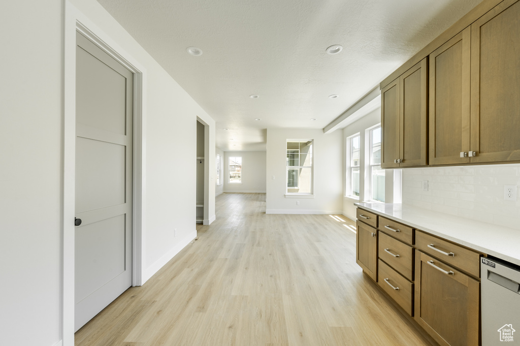 Kitchen with light wood-type flooring, backsplash, and dishwasher