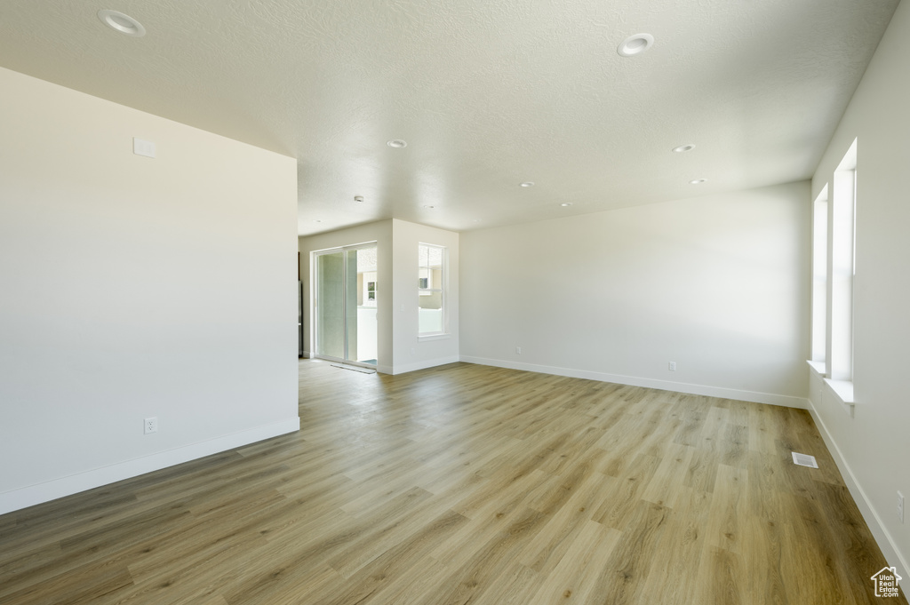 Unfurnished room featuring light hardwood / wood-style floors and a textured ceiling