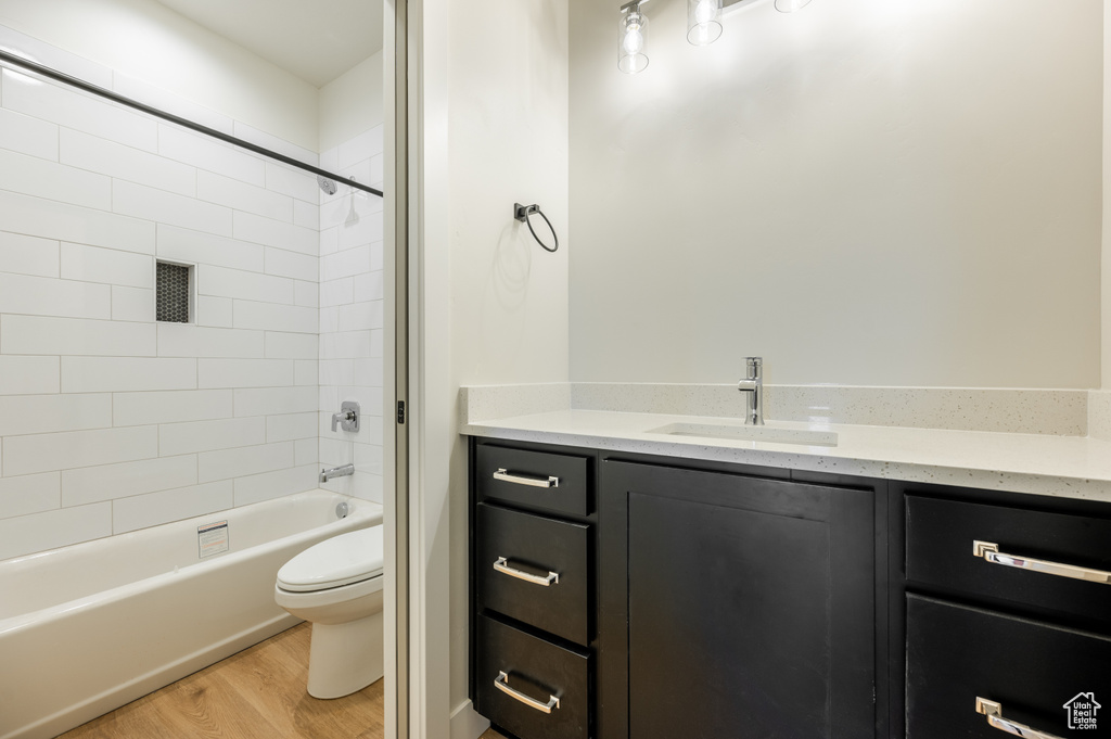 Full bathroom featuring hardwood / wood-style floors, tiled shower / bath, toilet, and vanity