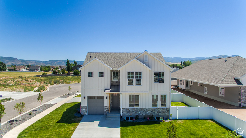 View of front facade featuring a mountain view, a garage, a front lawn, and central AC