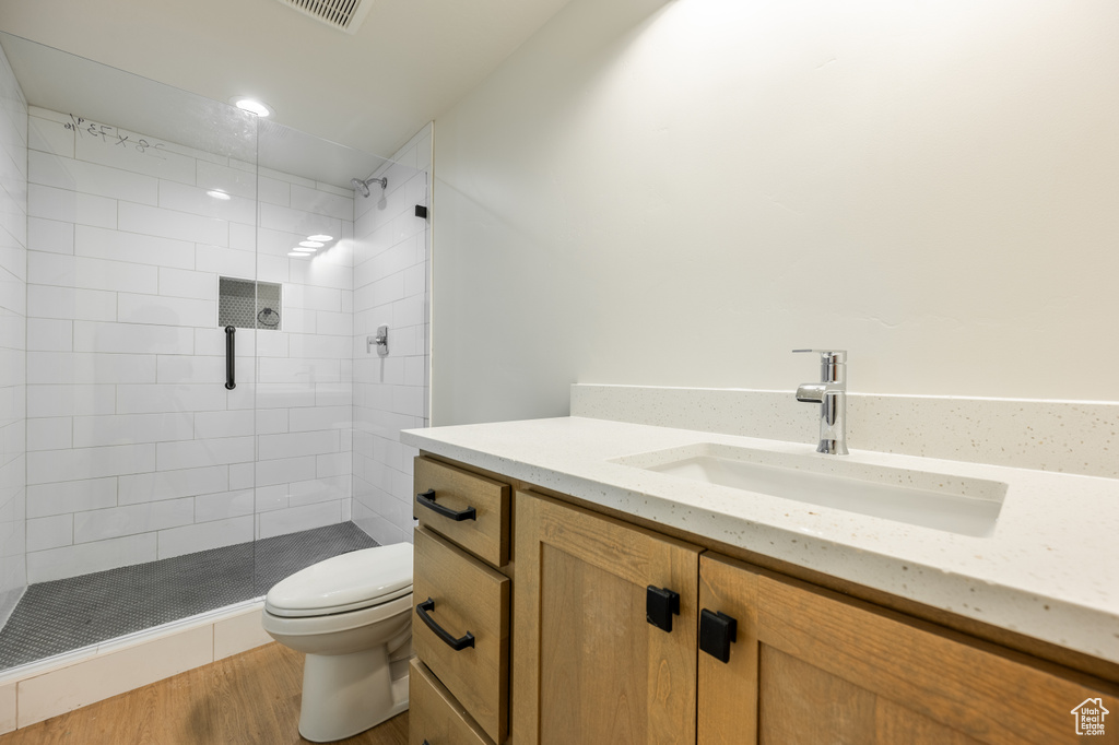 Bathroom featuring vanity, toilet, wood-type flooring, and a shower with door