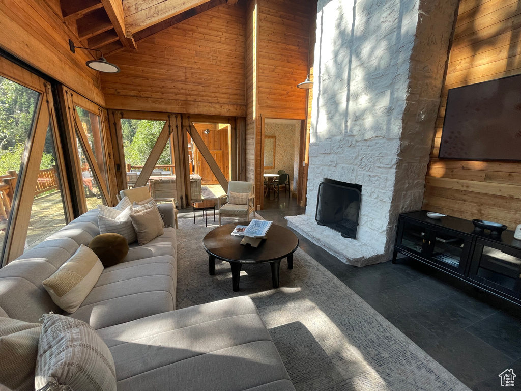 Living room featuring a healthy amount of sunlight, high vaulted ceiling, beam ceiling, and a fireplace