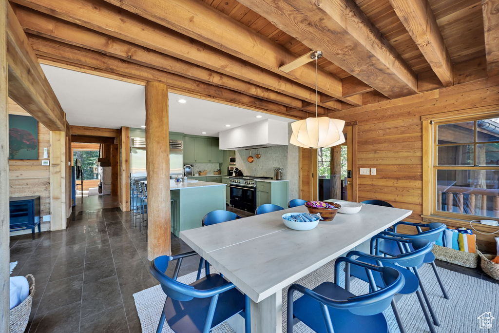 Dining room with wood walls, wood ceiling, a fireplace, and beamed ceiling