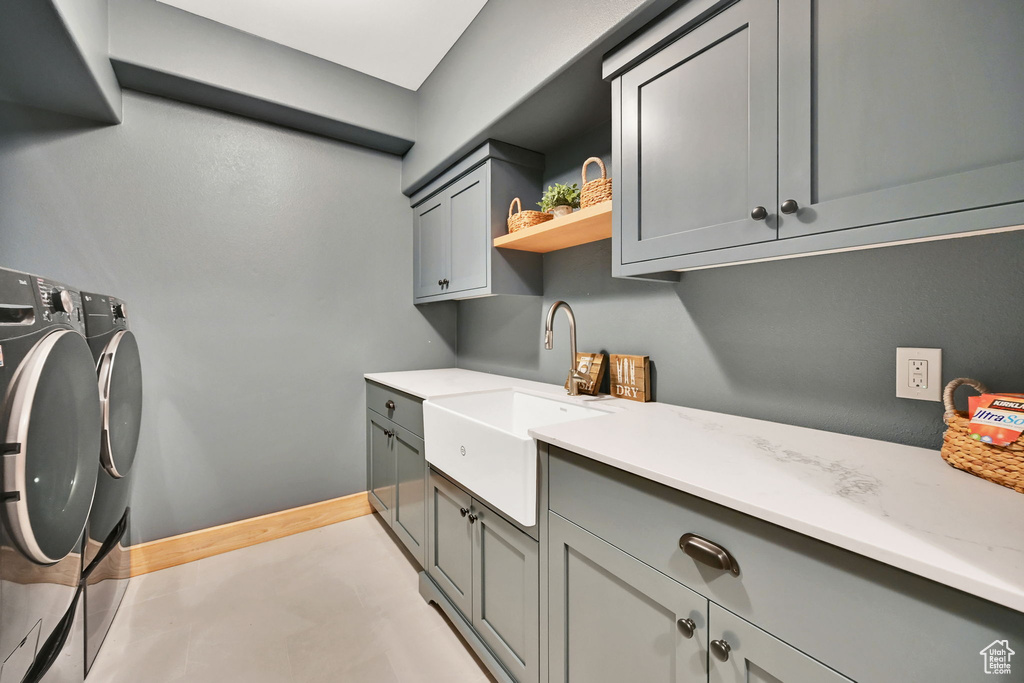 Laundry room with washing machine and clothes dryer, cabinets, and sink