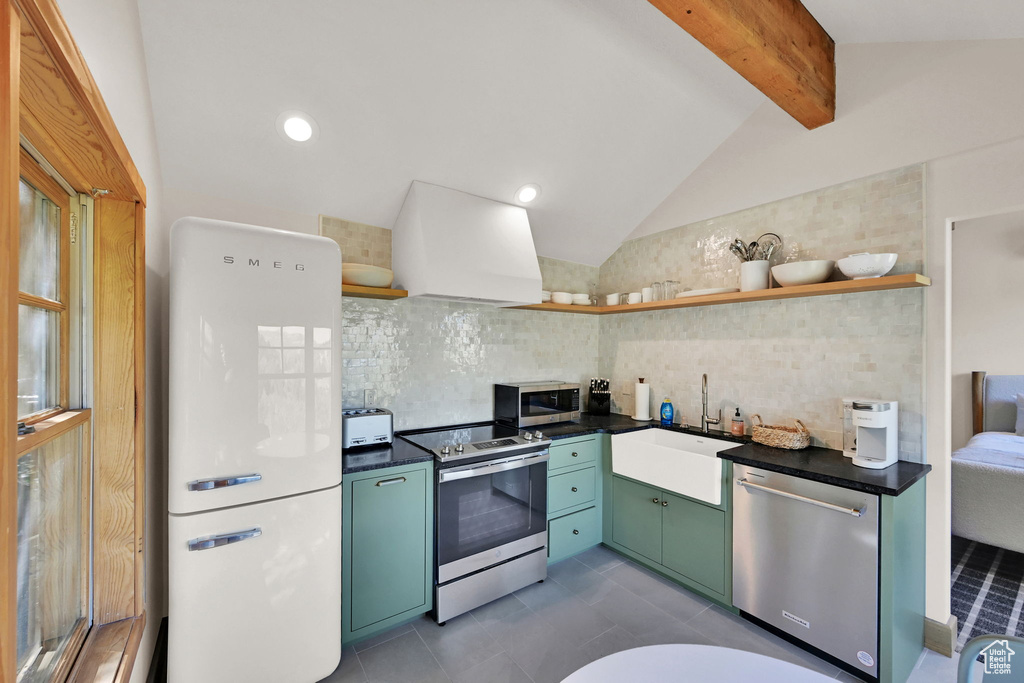 Kitchen featuring backsplash, premium range hood, appliances with stainless steel finishes, sink, and vaulted ceiling with beams