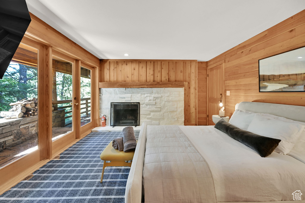 Bedroom featuring wood walls, a stone fireplace, and access to outside