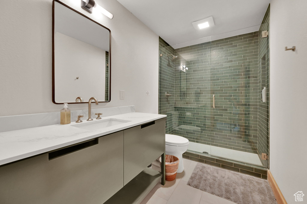 Bathroom featuring an enclosed shower, tile patterned floors, toilet, and vanity