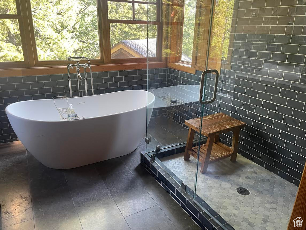 Bathroom with tile walls, plenty of natural light, and independent shower and bath