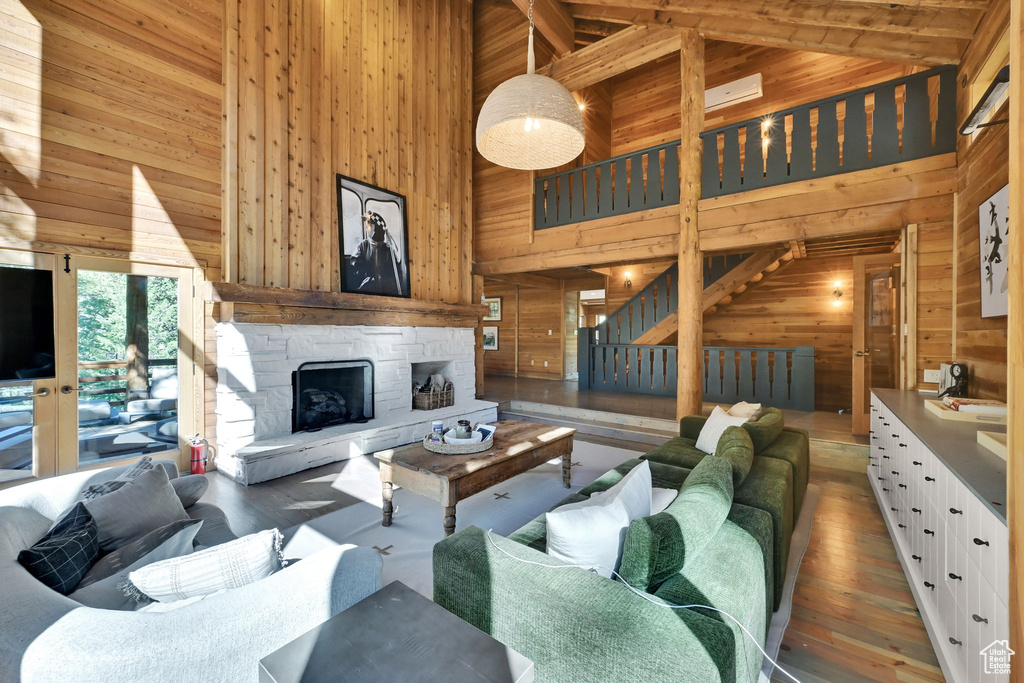 Living room featuring wood walls, a stone fireplace, high vaulted ceiling, and hardwood / wood-style flooring