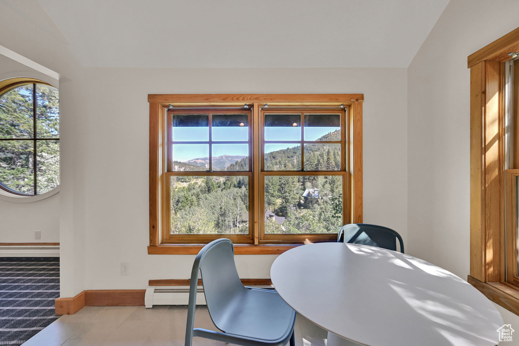 Office space with a baseboard heating unit, light tile patterned floors, and vaulted ceiling