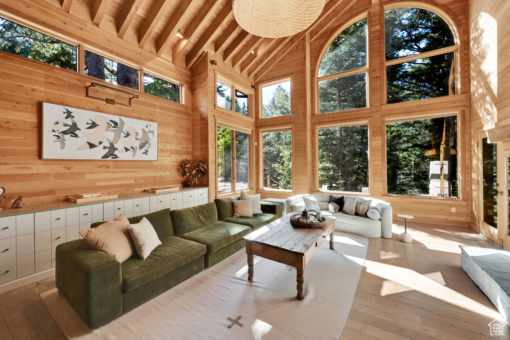 Living room with hardwood / wood-style floors, high vaulted ceiling, wood walls, and beamed ceiling