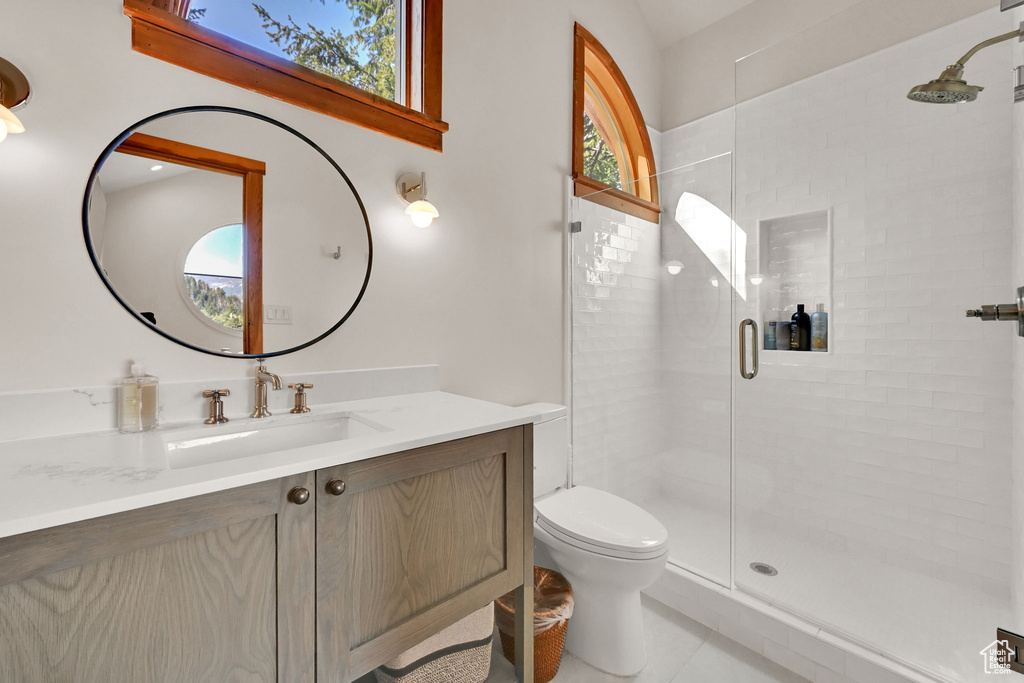 Bathroom featuring a shower with shower door, vanity, toilet, and a healthy amount of sunlight