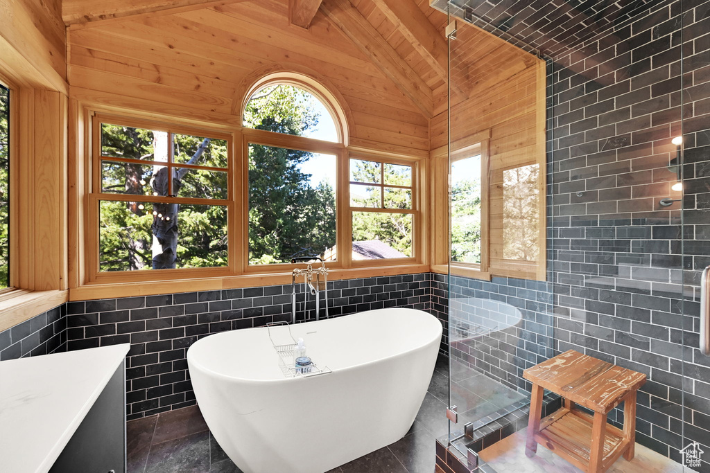 Bathroom with tile walls, a bath, and vaulted ceiling with beams