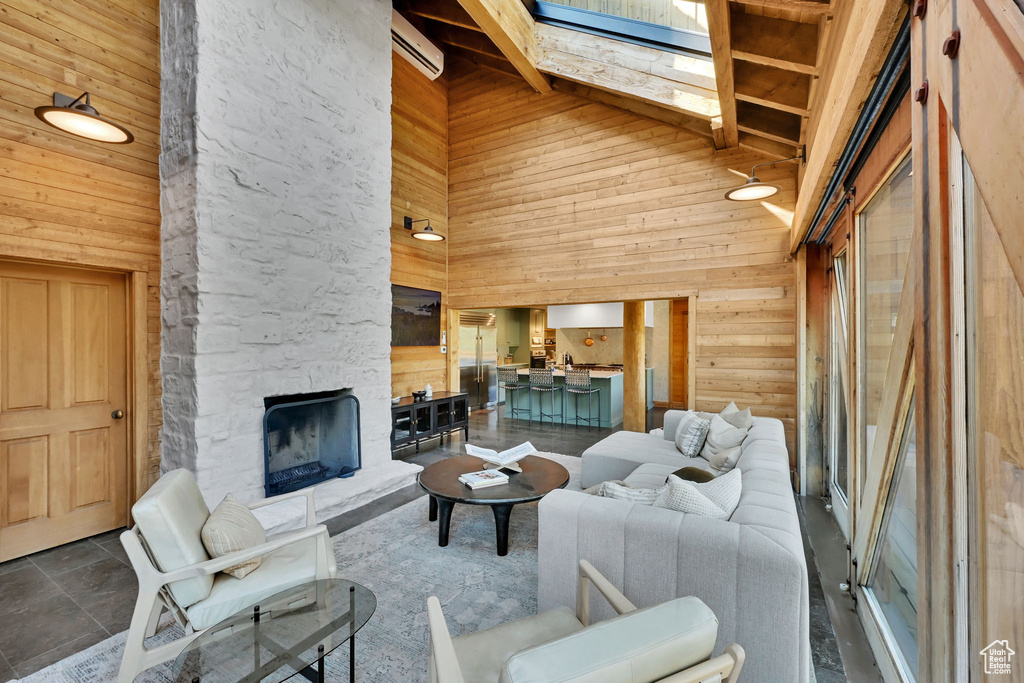 Tiled living room with a high ceiling, wood walls, and a fireplace