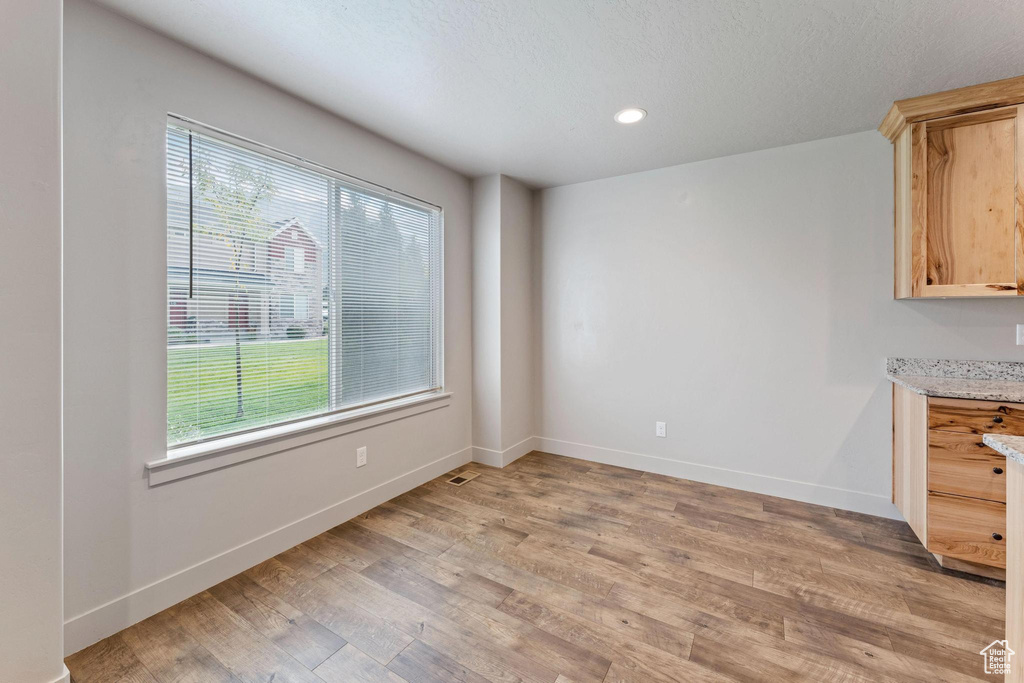 Unfurnished dining area with a textured ceiling, plenty of natural light, and wood-type flooring