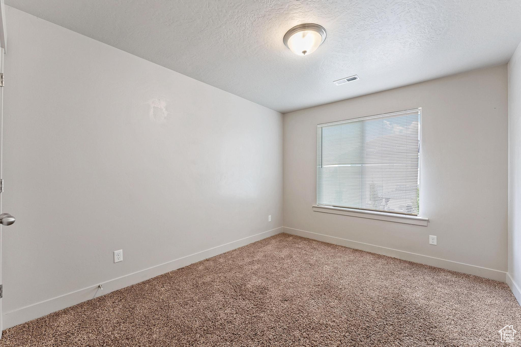 Empty room with a textured ceiling and carpet flooring