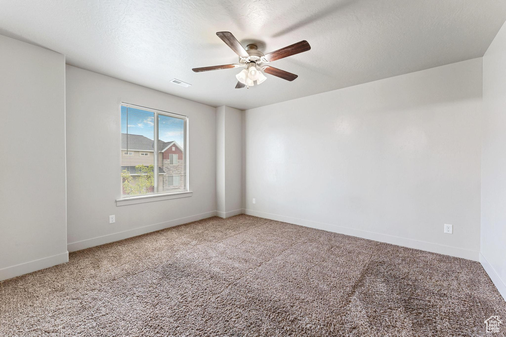 Unfurnished room with carpet flooring, ceiling fan, and a textured ceiling