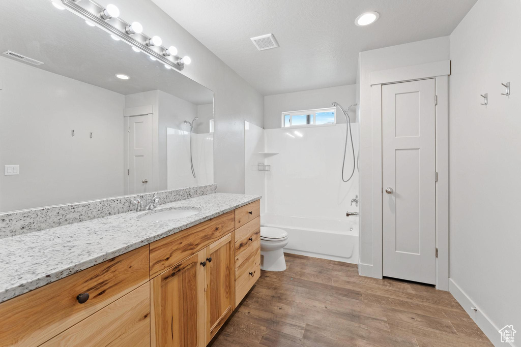 Full bathroom featuring toilet, hardwood / wood-style flooring,  shower combination, and vanity