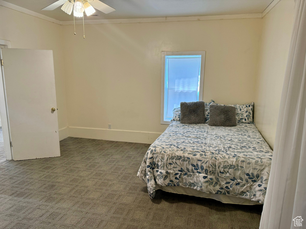 Carpeted bedroom featuring ceiling fan and crown molding