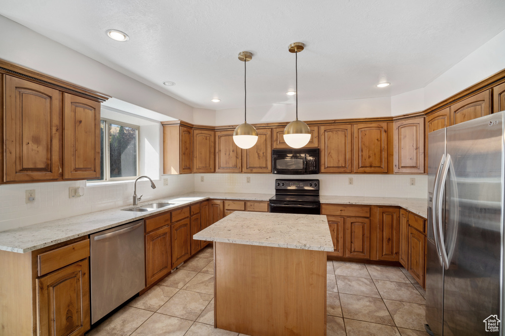 Kitchen featuring pendant lighting, black appliances, a center island, light stone countertops, and sink