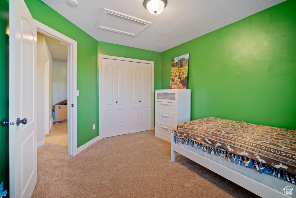 Bedroom with light colored carpet and a closet