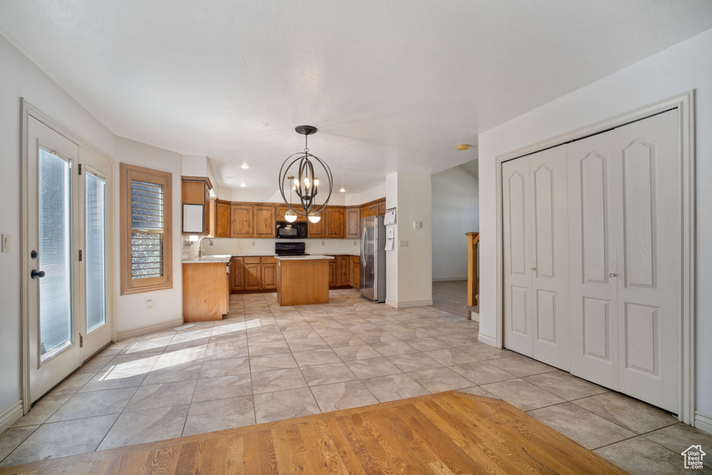 Kitchen with black appliances, a wealth of natural light, a chandelier, and light hardwood / wood-style flooring