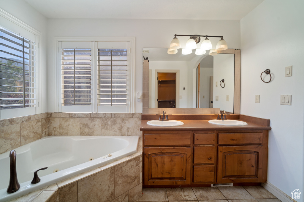 Bathroom with tile patterned flooring, a relaxing tiled tub, and vanity