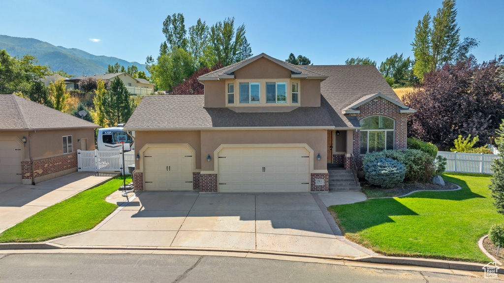 Front facade with a mountain view, a front yard, and a garage