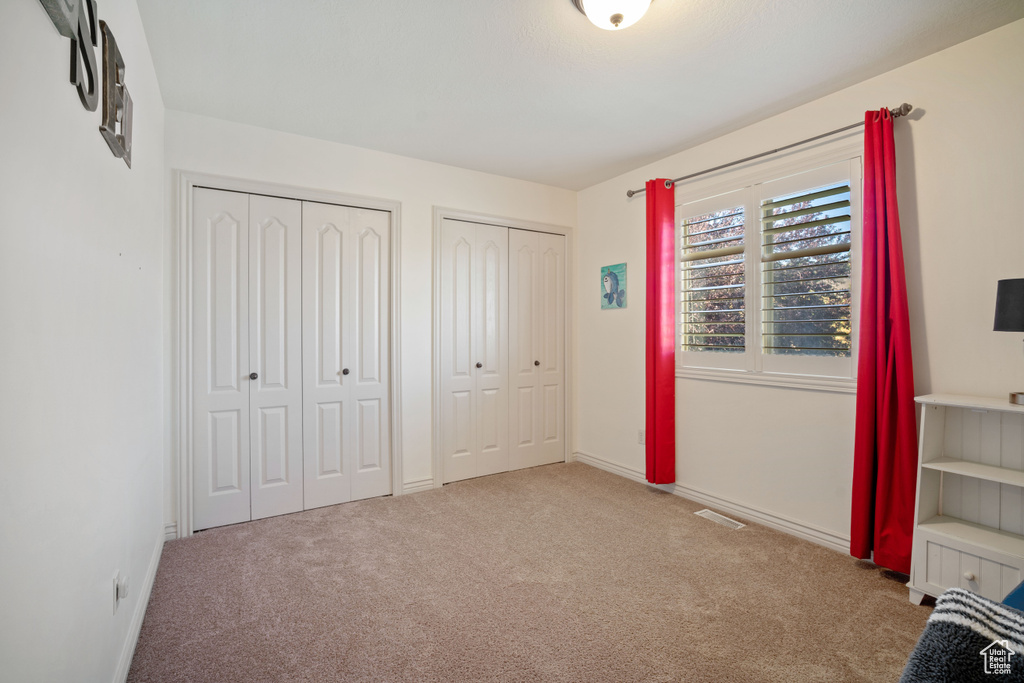 Unfurnished bedroom featuring carpet floors and multiple closets