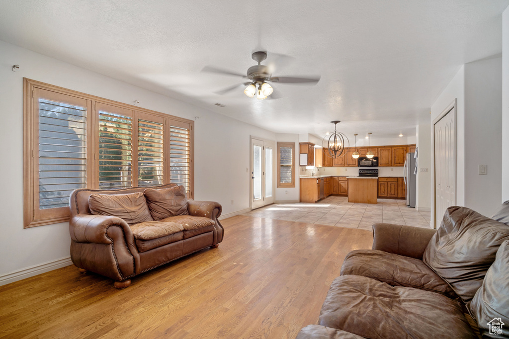 Living room featuring ceiling fan with notable chandelier, light hardwood / wood-style flooring, and sink