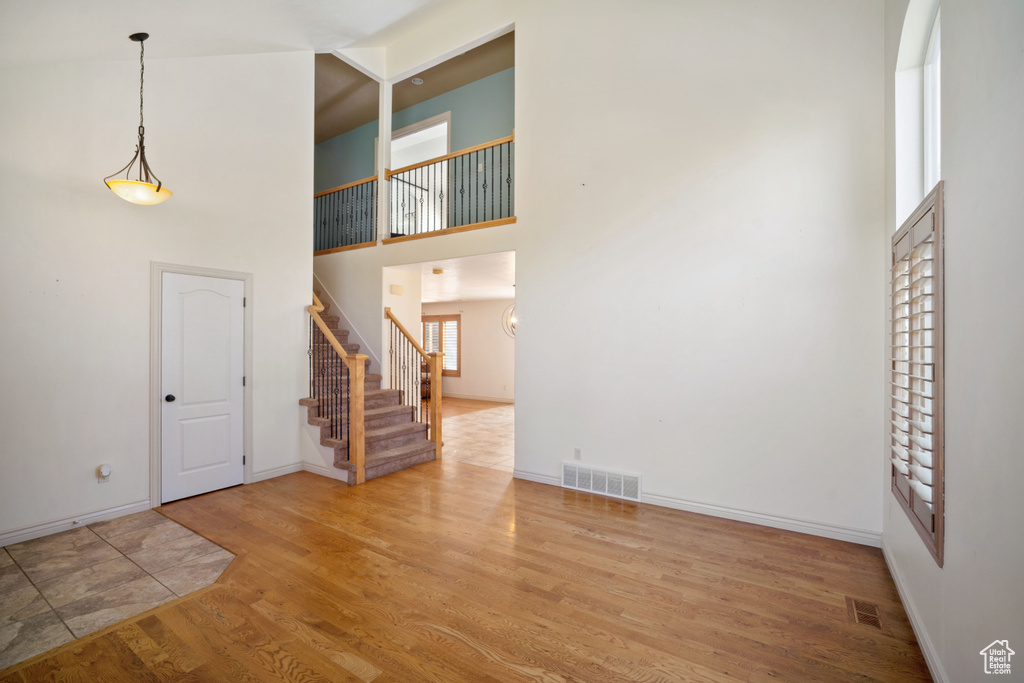 Unfurnished living room with hardwood / wood-style flooring and a high ceiling