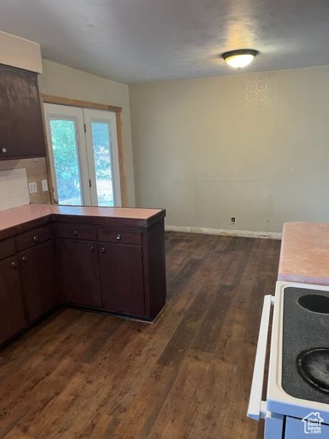 Kitchen with backsplash, stove, dark hardwood / wood-style flooring, and dark brown cabinetry