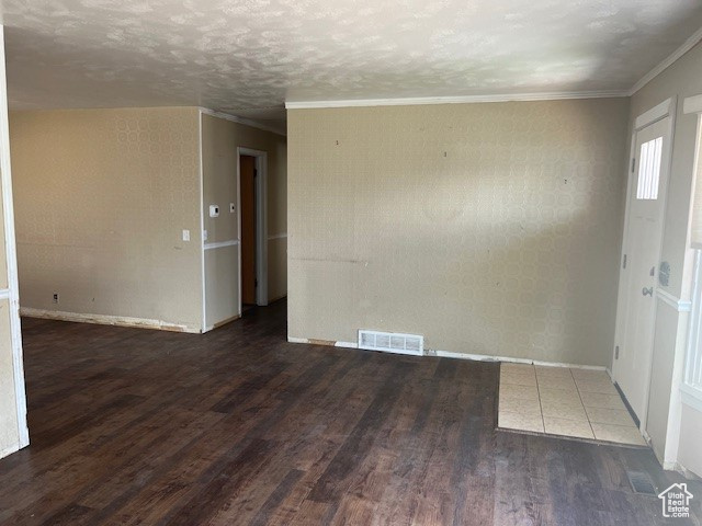 Empty room featuring a textured ceiling, crown molding, and hardwood / wood-style flooring